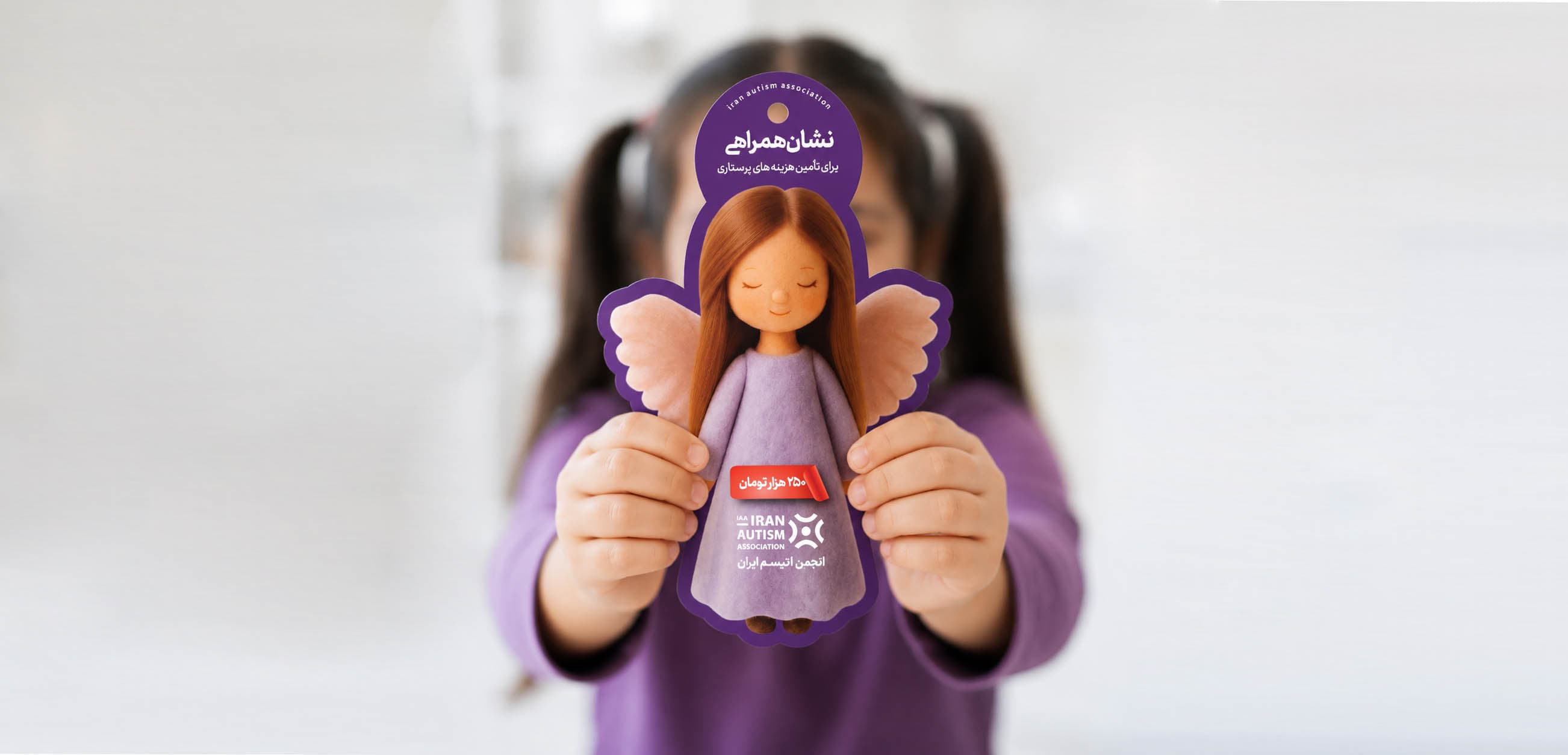 دختری نشان همراهی فرشته انجمن اتیسم ایران را در دست دارد